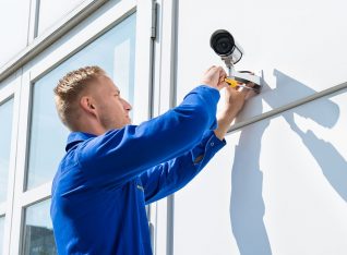 Technician Fixing Camera On Wall With Screwdriver