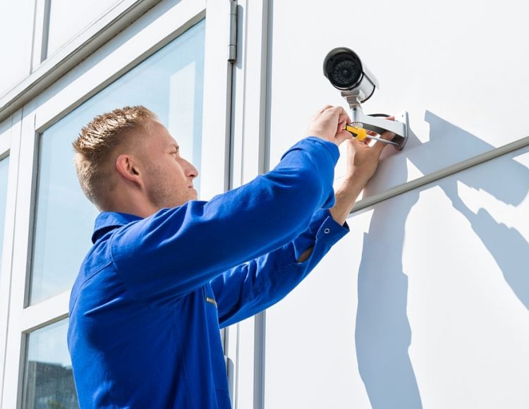 Technician Fixing Camera On Wall With Screwdriver